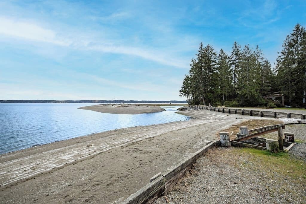 Ein Strand mit einer Holzpromenade, einem Sandbereich und einem bewaldeten Gebiet mit Bäumen.