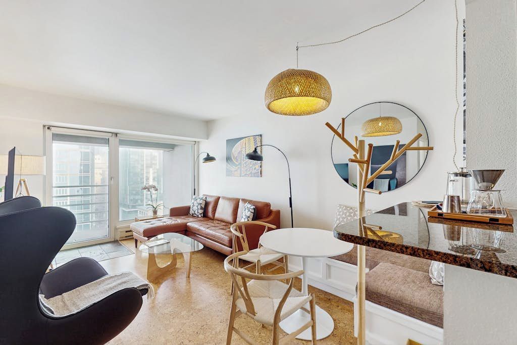 A modern living room with a sofa, chairs, a coffee table, and a dining area with a round table.