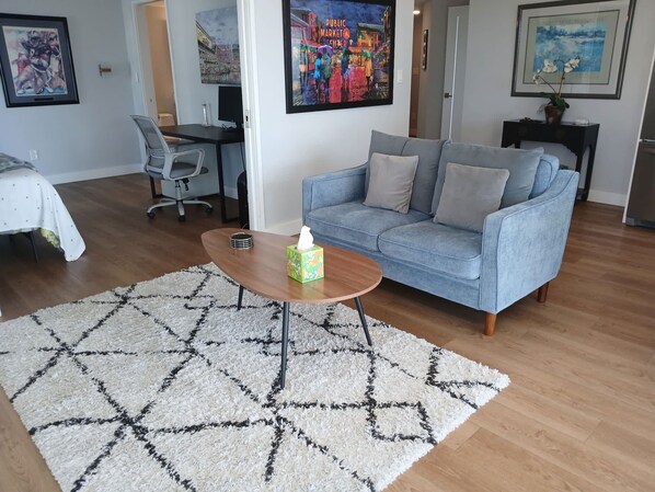 A living room with a blue sofa, a coffee table, and a patterned rug. - 2BR condo with water view, full kitchen, Washer Dryer (Seattle)