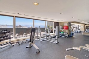 A gym with various exercise equipment, large windows, and a view of the city. - Dog-friendly, bay view suite with walk score of 100 (Seattle)