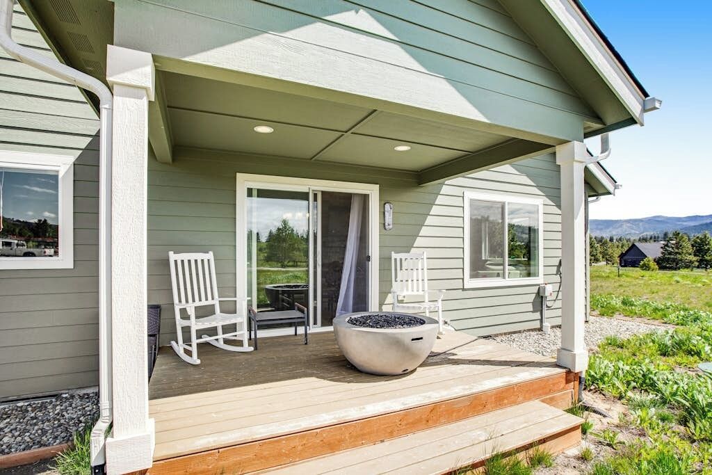 A covered porch with a fire pit, two rocking chairs, and a view of the landscape.