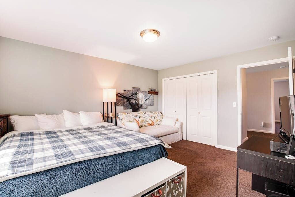 Une chambre à coucher avec un lit, une table de chevet, une lampe, une commode et une porte.