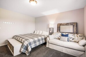 Une chambre à coucher avec un lit, un banc, un canapé, une lampe et un miroir.