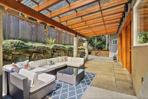 A covered outdoor seating area with a sofa and chairs, a coffee table, and a patterned rug. - 4BR home with pool, hot tub & great location (Tacoma)