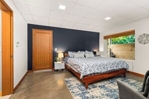 A bedroom with a bed, a nightstand, a chair, a window with a view, and a door. - 4BR home with pool, hot tub & great location (Tacoma)