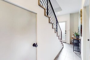 A modern interior with a staircase, a door, and a small table with a plant. - 3 BR townhome with rooftop deck and city access (Seattle)
