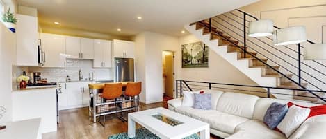 Ein modernes Apartment mit Wohnzimmer, Küche und Treppe.