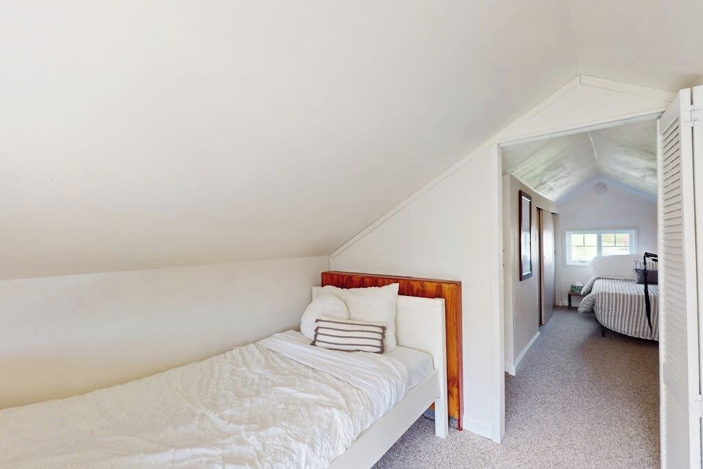 A bedroom with a single bed, a wooden headboard, and a carpeted floor.