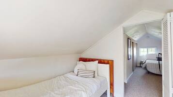 A bedroom with a single bed, a wooden headboard, and a carpeted floor.