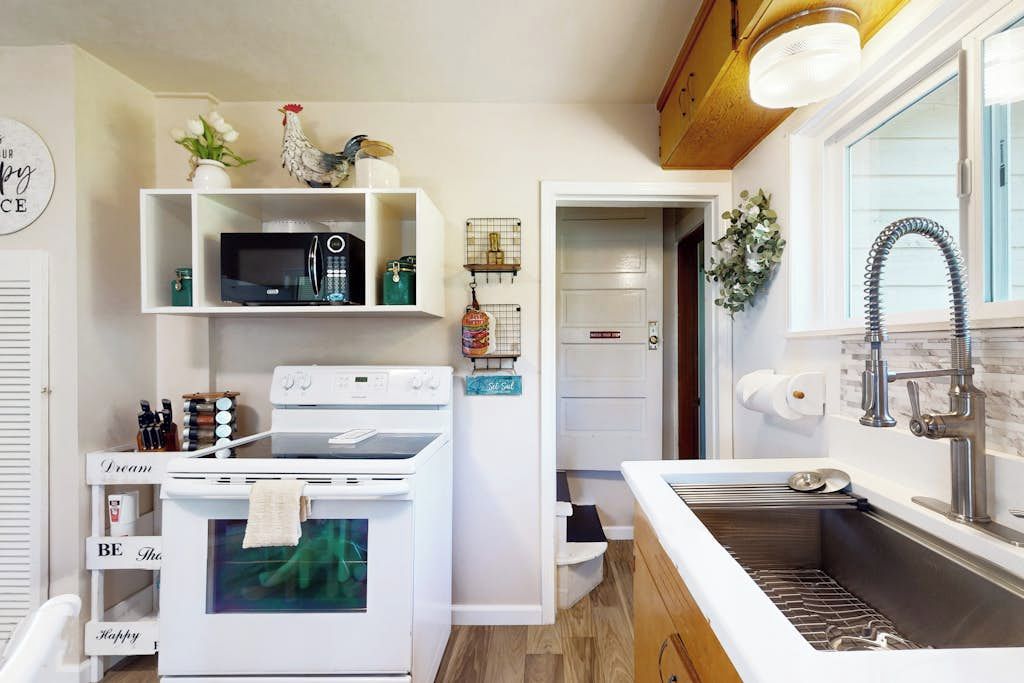 A compact kitchen with white appliances, a built-in microwave, and a stainless steel sink.