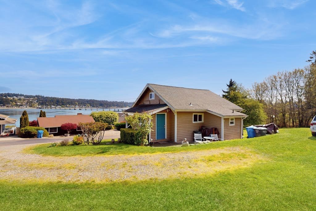 A single-story house with a front porch, a small attached garage, and a view of a lake.