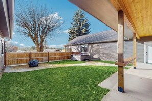 A backyard with a wooden deck, a covered patio, and a fenced area. - 3BR home with hot tub, pool table & wifi (Ronald)