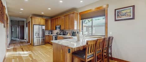 Una cocina amplia con armarios de madera, electrodomésticos de acero inoxidable y una isla grande con asientos.
