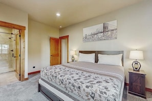 A bedroom with a large bed, two bedside lamps, a wooden headboard, a door, and a wall-mounted artwork. - 3BR home with hot tub, pool table & wifi (Ronald)