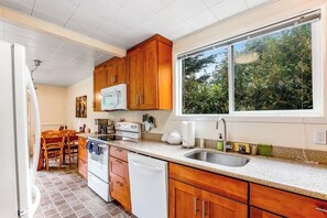 Una cocina compacta con muebles de madera, un refrigerador blanco, un microondas y un lavavajillas.