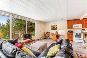 A living room with a sofa, television, and a dining area with chairs and a table.