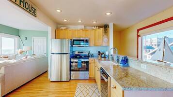 A modern kitchen with stainless steel appliances, wooden cabinets, and a large window.