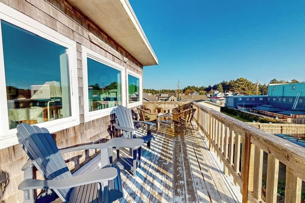 A wooden deck with Adirondack chairs and a view of a town.