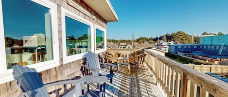 A wooden deck with Adirondack chairs and a view of a town.