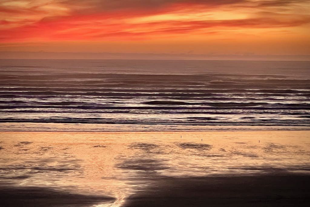 A beach with waves and a sunset.