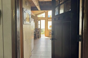 A hallway with a wooden door leading to a room with a window and a chair. - Ocean-view dog-friendly 1BR, private path to beach (Copalis Beach)
