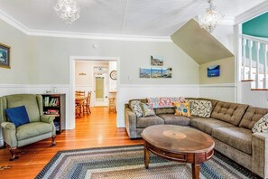 A living room with a sectional sofa, a round coffee table, a green armchair, and a bookshelf. - Restored 3BR Dog Friendly - Deck - Firepit - Washer Dryer (Sequim)