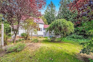 A residential property with a white house, a well-maintained lawn, and various trees. - Restored 3BR Dog Friendly - Deck - Firepit - Washer Dryer (Sequim)