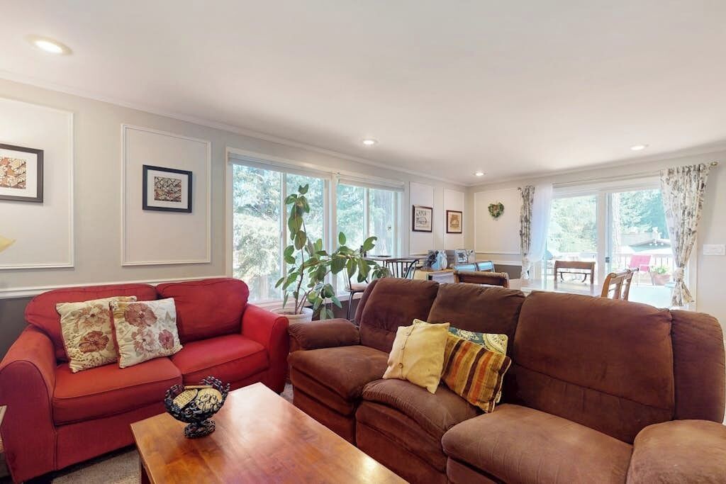 A living room with two sofas, a coffee table, and a dining area with a table and chairs.