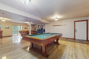 Una habitación amplia con mesa de billar, un sofá y una chimenea.