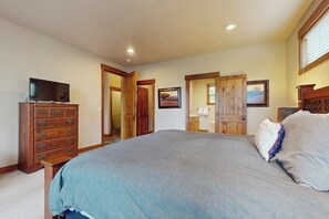 Un dormitorio con una cama grande, un aparador de madera y un televisor sobre un mueble.