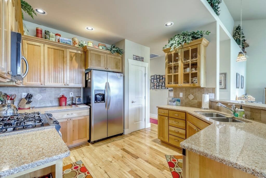 A modern kitchen with wooden cabinets, stainless steel appliances, and a granite countertop.