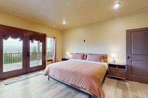 Een slaapkamer met een bed, nachtkastjes, een deur en een balkon.