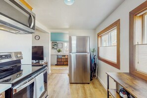 A modern kitchen with stainless steel appliances, wooden flooring, and a view into the adjacent living area. - 1BR Home in the Historic Marina District -1 dog ok (Westport)