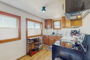 Eine kleine Küche mit Holzausstattung, einem eingebauten Backofen und einem Fenster mit Jalousien.