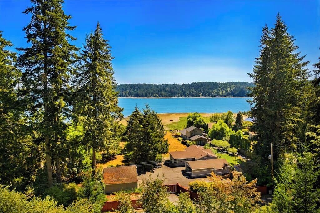 Un quartier résidentiel avec des maisons, un ciel d’un bleu éclatant et un lac en arrière-plan.