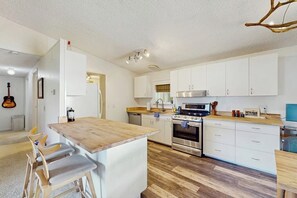 A modern kitchen with white cabinets, a wooden island, and a built-in oven. - 2 BR water view house, dog friendly amenities (Belfair)