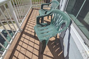 Een balkon met een metalen hekwerk en twee groene plastic stoelen.