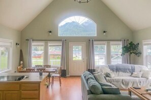 Ein großzügiger Wohnbereich mit hoher Decke, einem Esstisch und einer Couch.