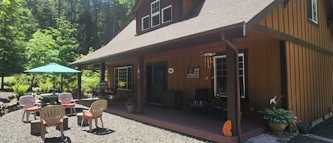A wooden cabin with a porch, outdoor seating, and a flag.