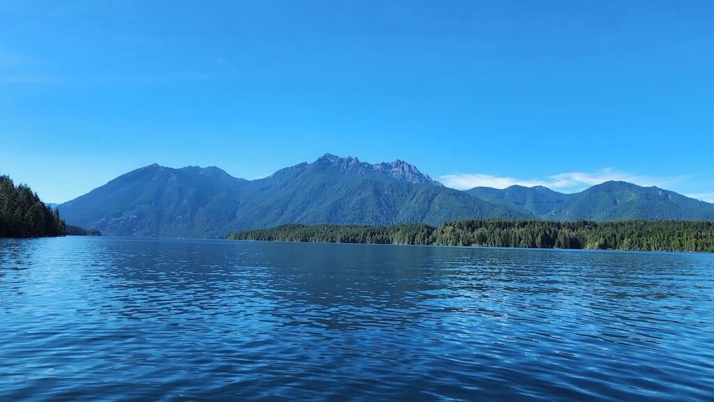 Un lago tranquilo con montañas al fondo.