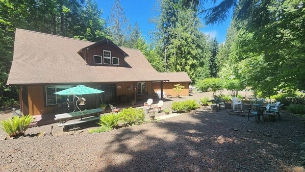 A lodge with a covered patio, outdoor seating, and a gravel area. - 2BR Cozy cabin getaway with firepit, and patio (Hoodsport)
