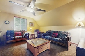 Ein Wohnzimmer mit Deckenventilator, zwei Sofas, einem Couchtisch und einer Lampe.