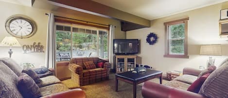 Una sala de estar con sofás de cuero, una mesa de centro, un televisor y una chimenea.