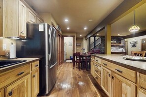 Una cocina con armarios de madera, un refrigerador de acero inoxidable y un comedor con mesa y sillas.
