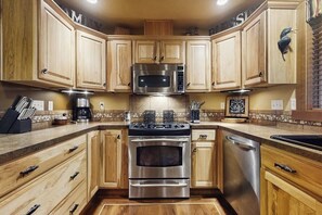 A kitchen with wooden cabinets, stainless steel appliances, and a tiled backsplash. - 2BR Cozy cabin getaway with firepit, and patio (Hoodsport)