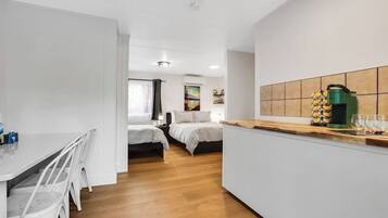 Una habitación de hotel compacta con kitchenette, zona de comedor y cama.