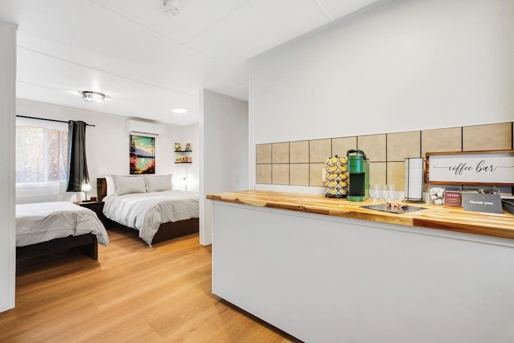 A hotel room with two beds, a kitchenette, and a coffee bar.