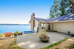 A house with a view of a lake, a hot tub, and a covered patio area. - Updated 3BR Bayview - Balcony - Firepit (Allyn)