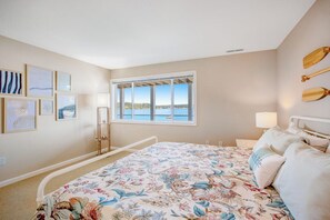 Un dormitorio con cama, ventana con vistas y pared con cuadros.