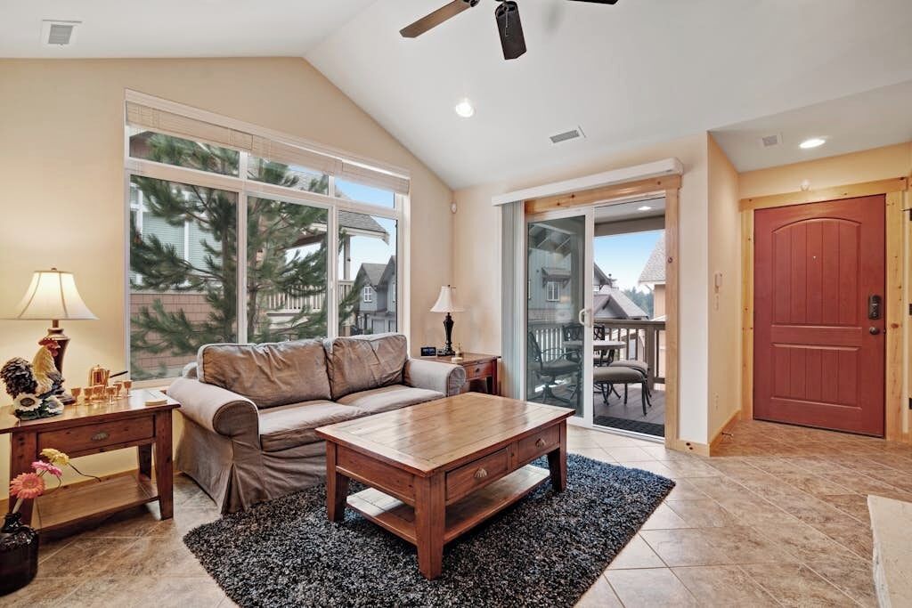 A living room with a sofa, coffee table, and a view through a sliding glass door.